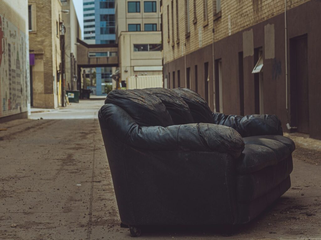 An old leather sofa dumped in a brick lane waiting for uplift